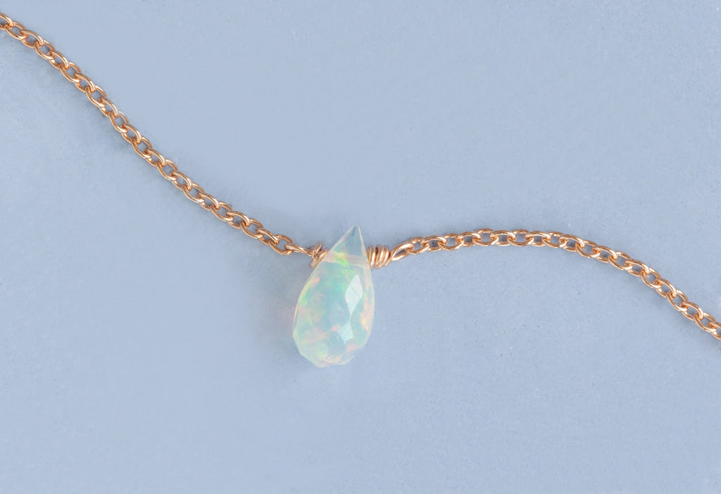 Close Up of Natural Opal Teardrop Bracelet in Rose Gold on Blue Background