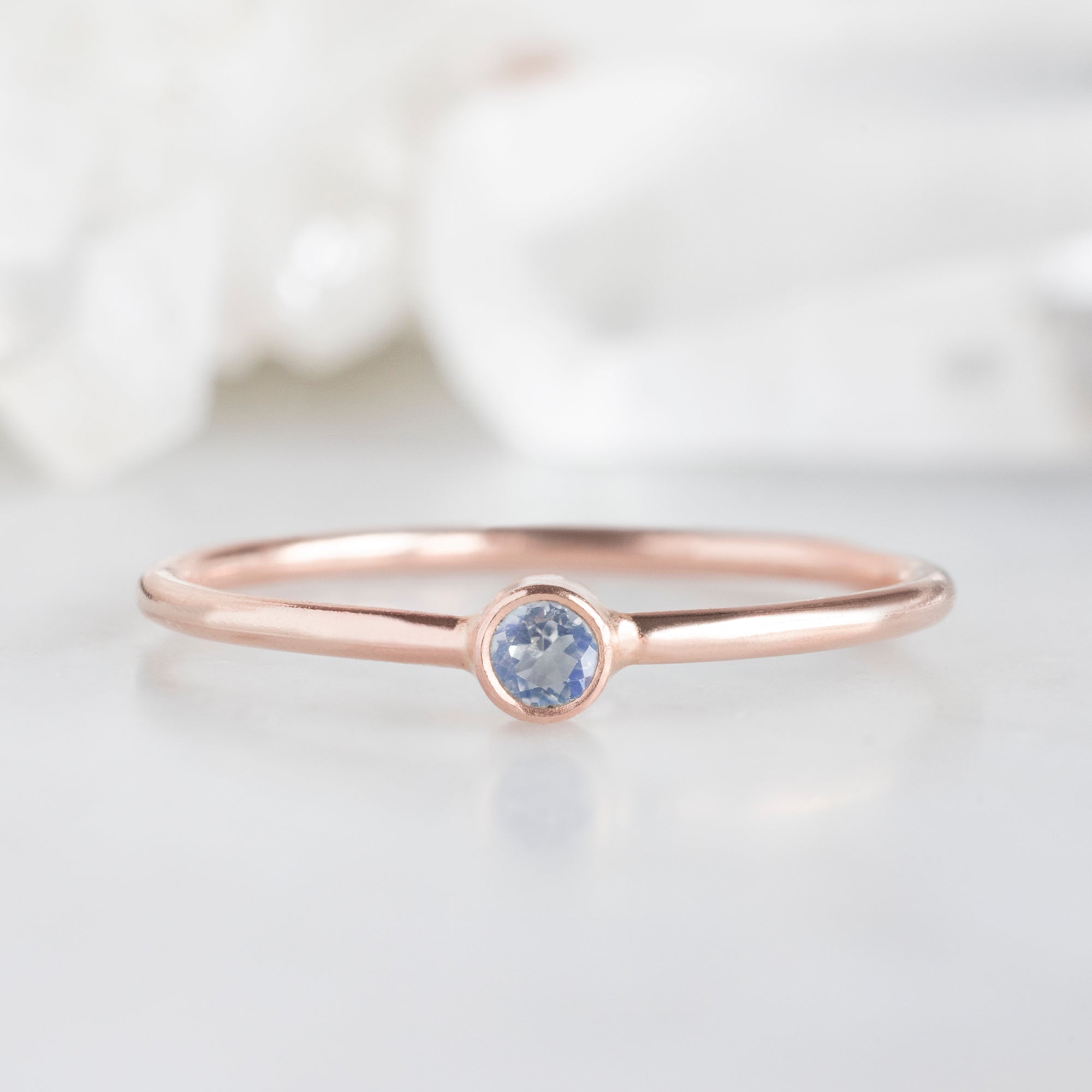 Custom Moonstone Birthstone Stacking Ring | 10K Rose Gold, Displayed on marble surface with white blurred background.