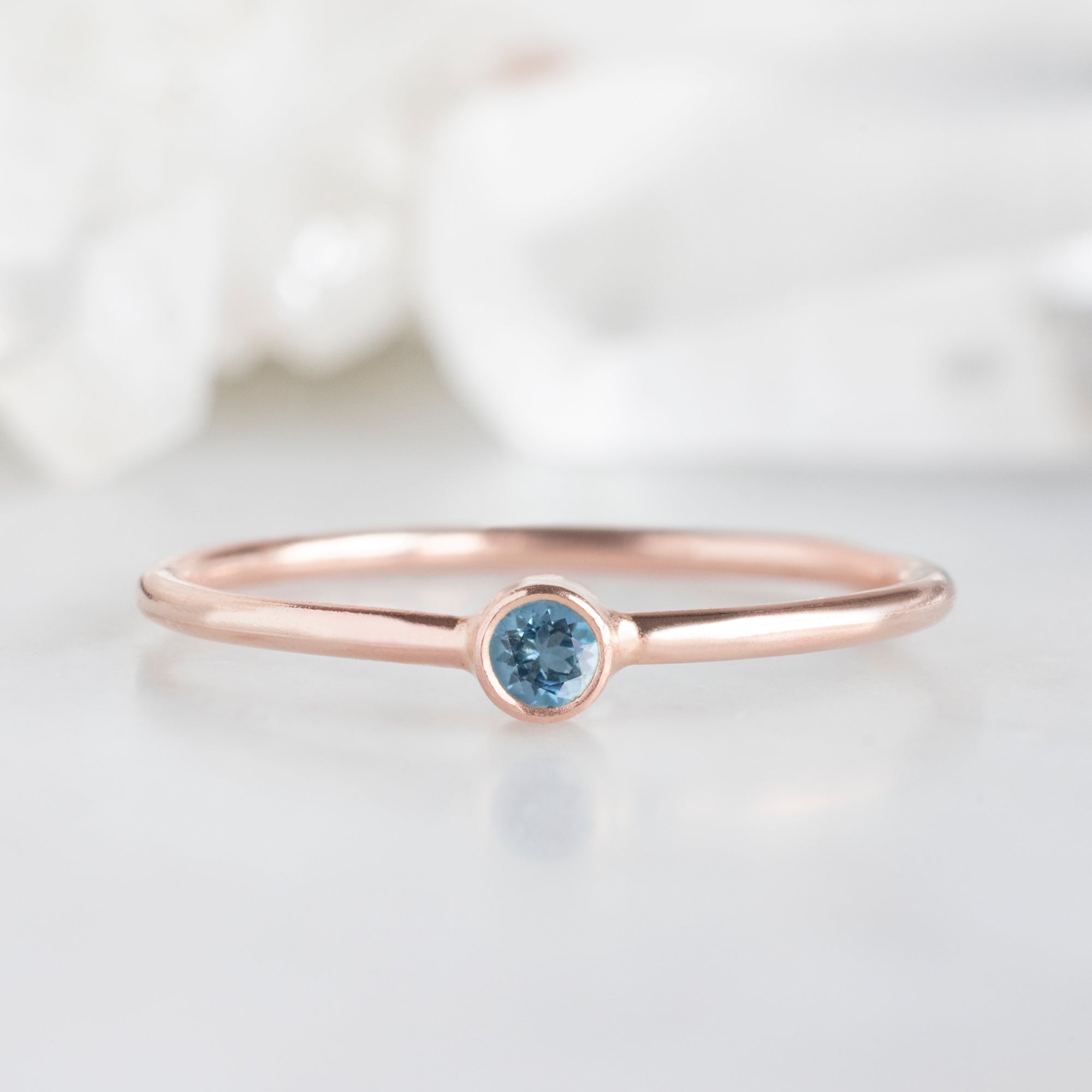 Custom Aquamarine Birthstone Stacking Ring | 10K Rose Gold with white blurred background.