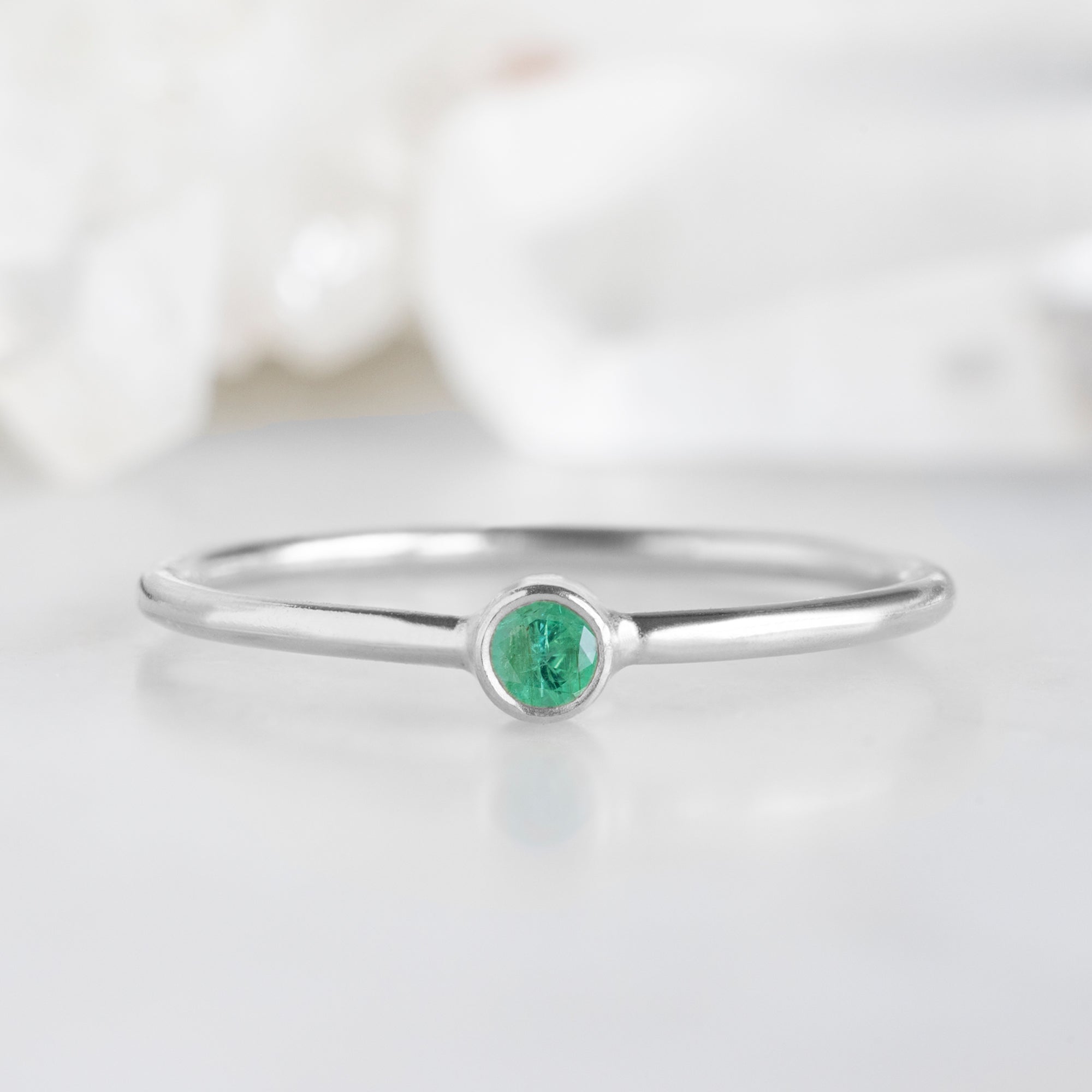 Custom Emerald Birthstone Stacking Ring | 10K White Gold. Displayed on marble surface with white blurred background.
