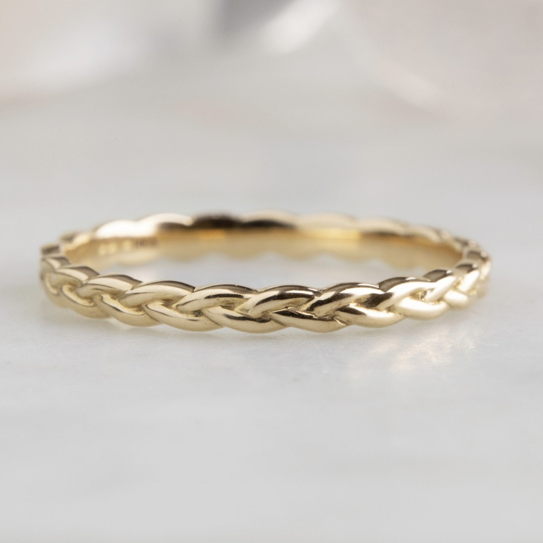 The Gold Braided Stacking Ring in 14K Yellow Gold on White Marble Tile
