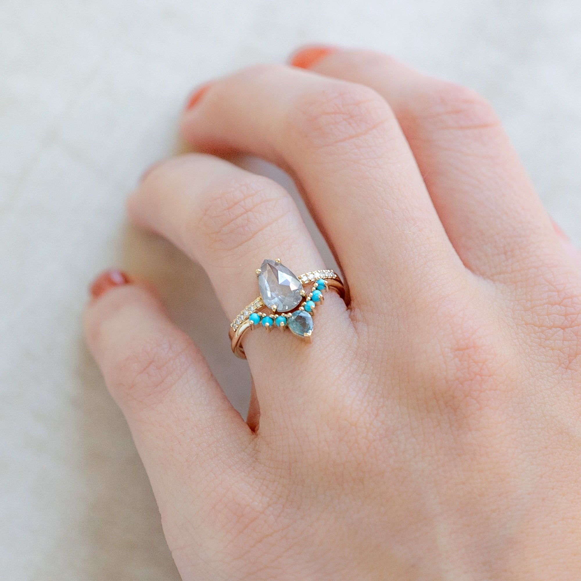 Montana Sapphire and Turquoise Sunburst Stacking Band in 14K Yellow Gold stacked with Pear Diamond Engagement Ring on model