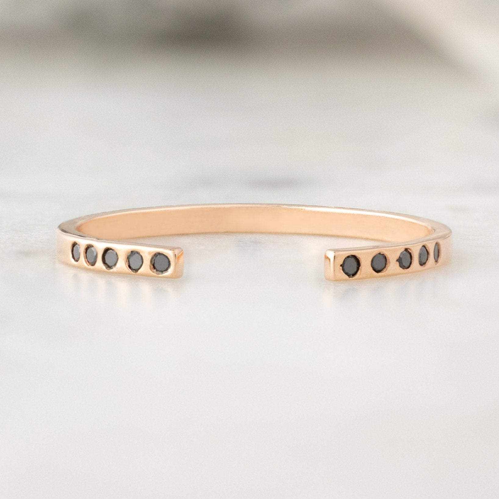 Open Cuff Flush Set Black Diamond Pavé Stacking Band in 14K Rose Gold on White Marble Surface