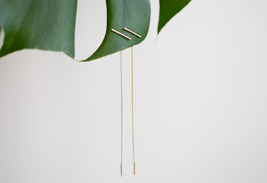 Linea Thread Earrings hanging on leaf