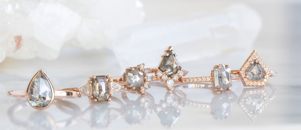 Line of Rose Gold Salt and Pepper Diamond Engagement Rings on Marble Tile