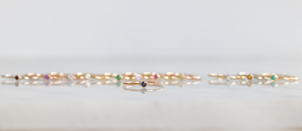 Birthstone Stacker Rings lined up with sapphire ring in front