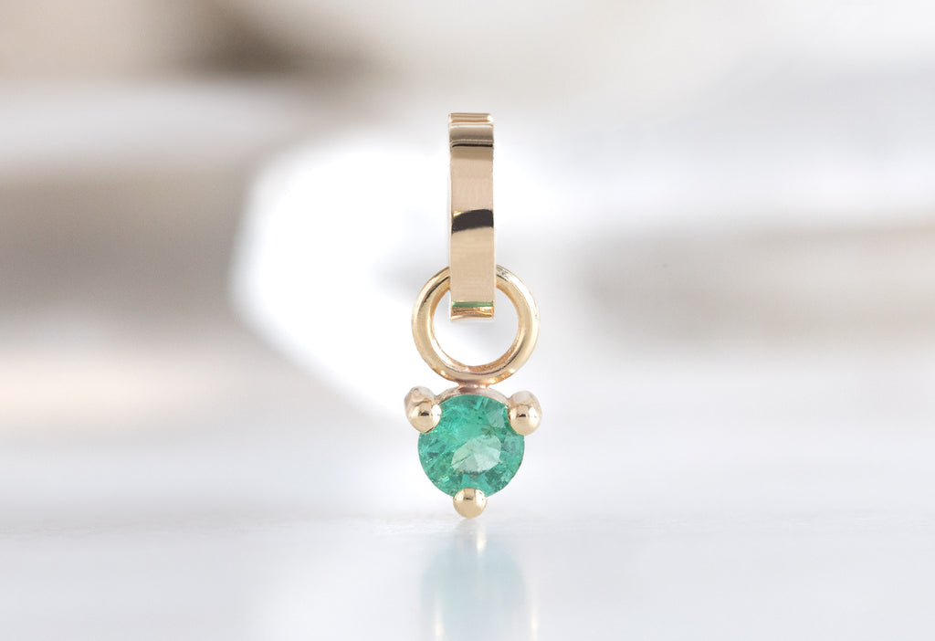 10k Yellow Gold Emerald Birthstone Charm on White Marble Tile
