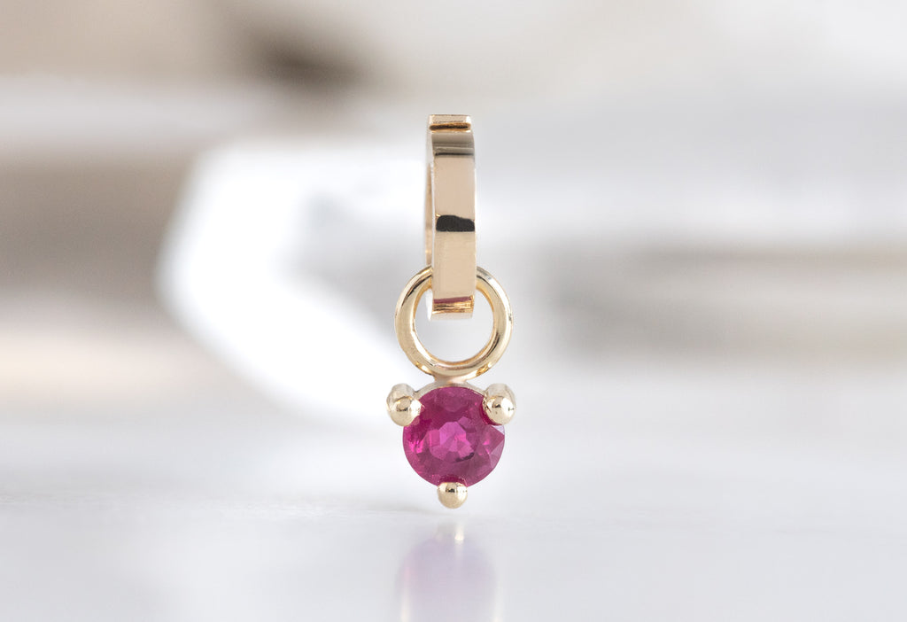 10k Yellow Gold Ruby Birthstone Charm on White Marble Tile