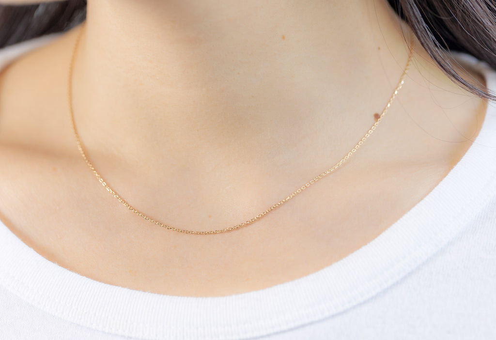 Yellow Gold Diamond-Cut Cable Chain Charm Necklace on Model wearing white boatneck shirt