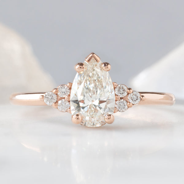 The Ivy Ring with a 0.65ct Pear White Diamond in 14K Rose Gold on White and Blue Background