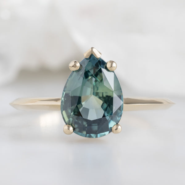 The Sage Ring with a 2.04ct Pear Teal Sapphire in 14 Yellow Gold on White Marble