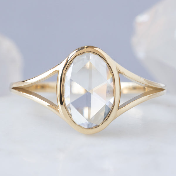 The Magnolia Ring with a 1.26ct Oval Lab Grown White Diamond in 14K Yellow Gold on Pale Blue Bbackground