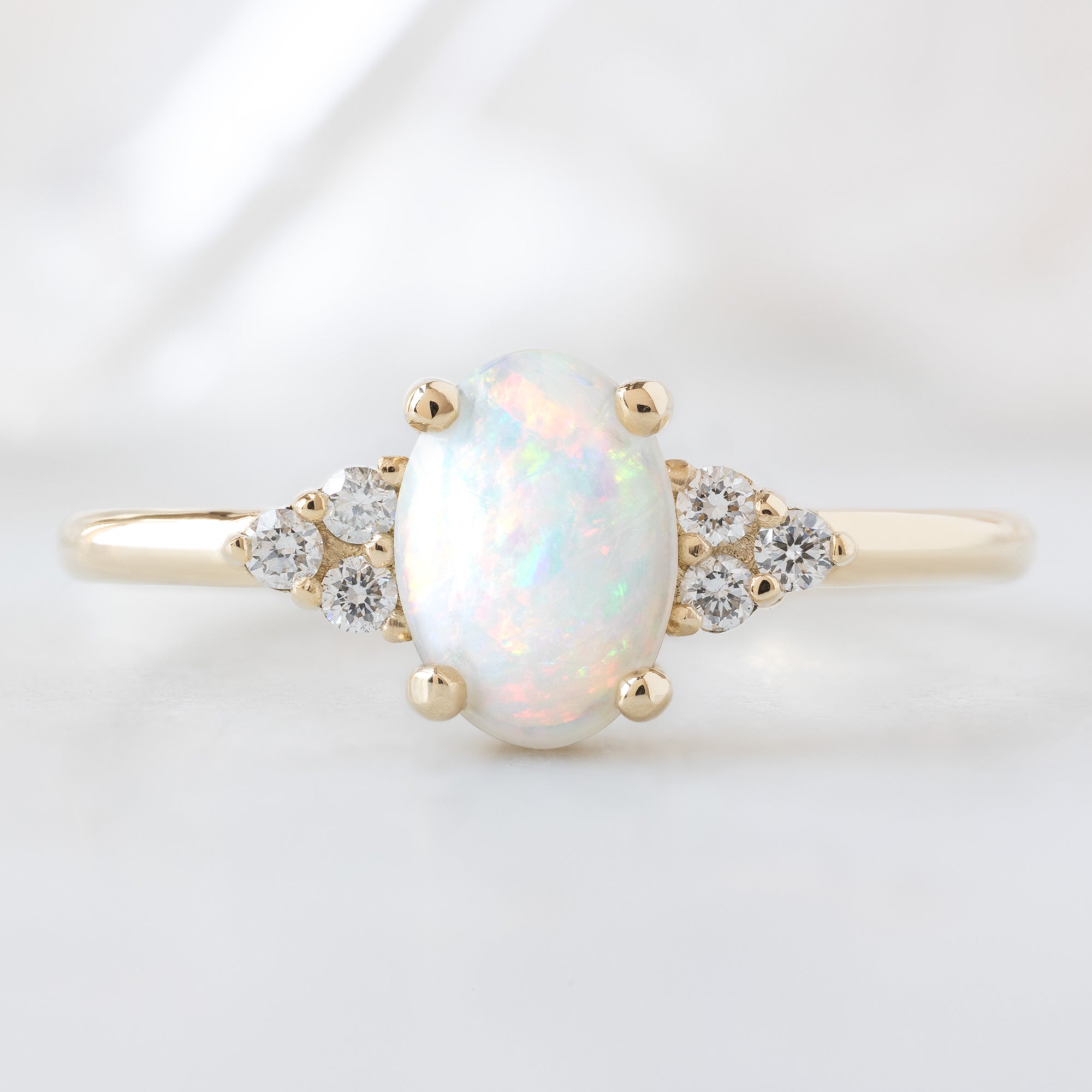 The Ivy Ring with a 0.44ct Oval Australian Opal in 14K Yellow Gold  on White Marble Surface