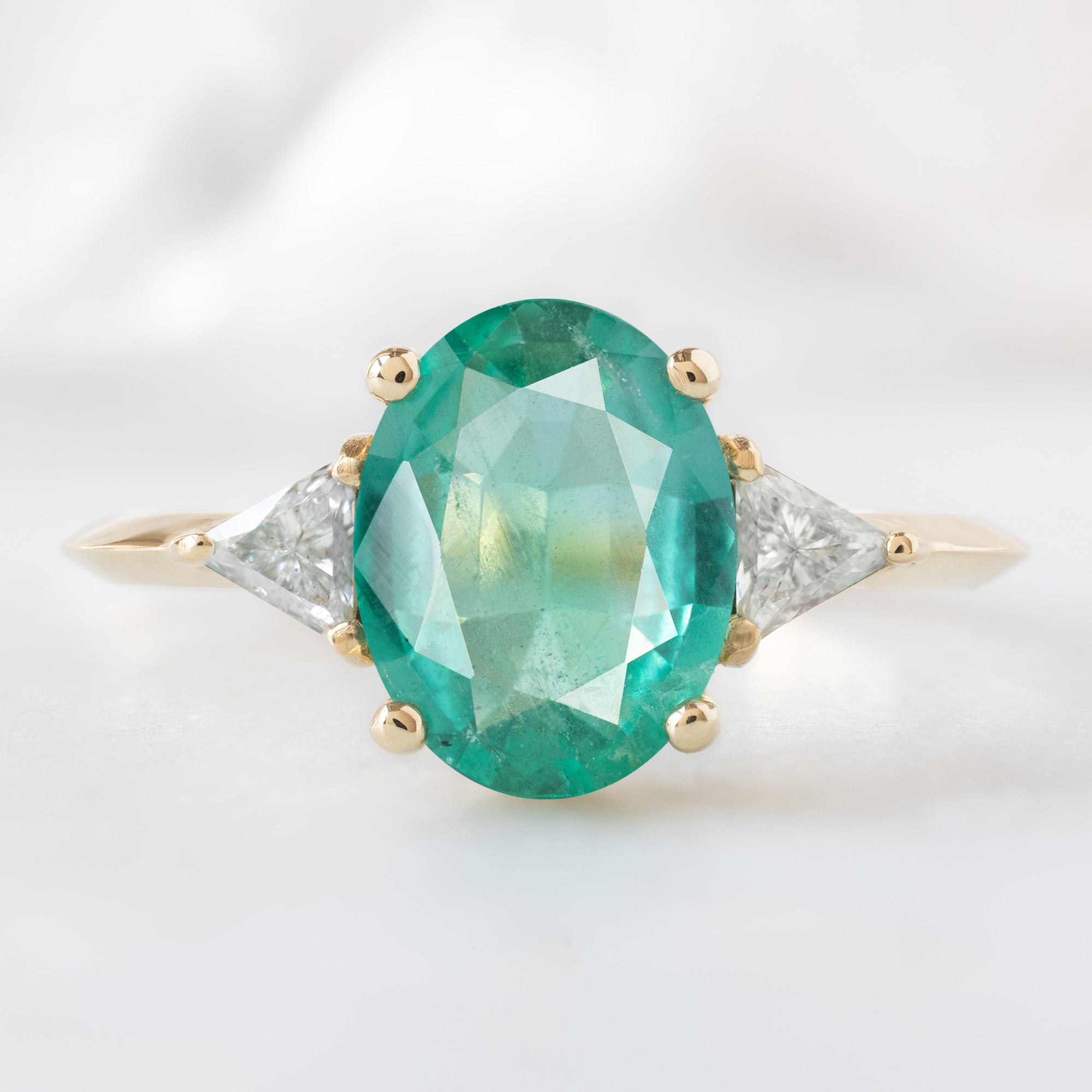 The Jade Ring with a 1.27ct Oval Emerald in 14K Yellow Gold on White Marble Surface