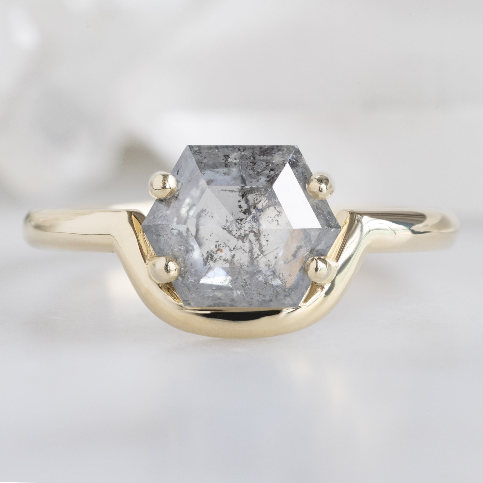 The Wave Ring with a 1.37ct Hexagon Salt and Pepper Diamond in 14K Yellow Gold on White Marble Surface