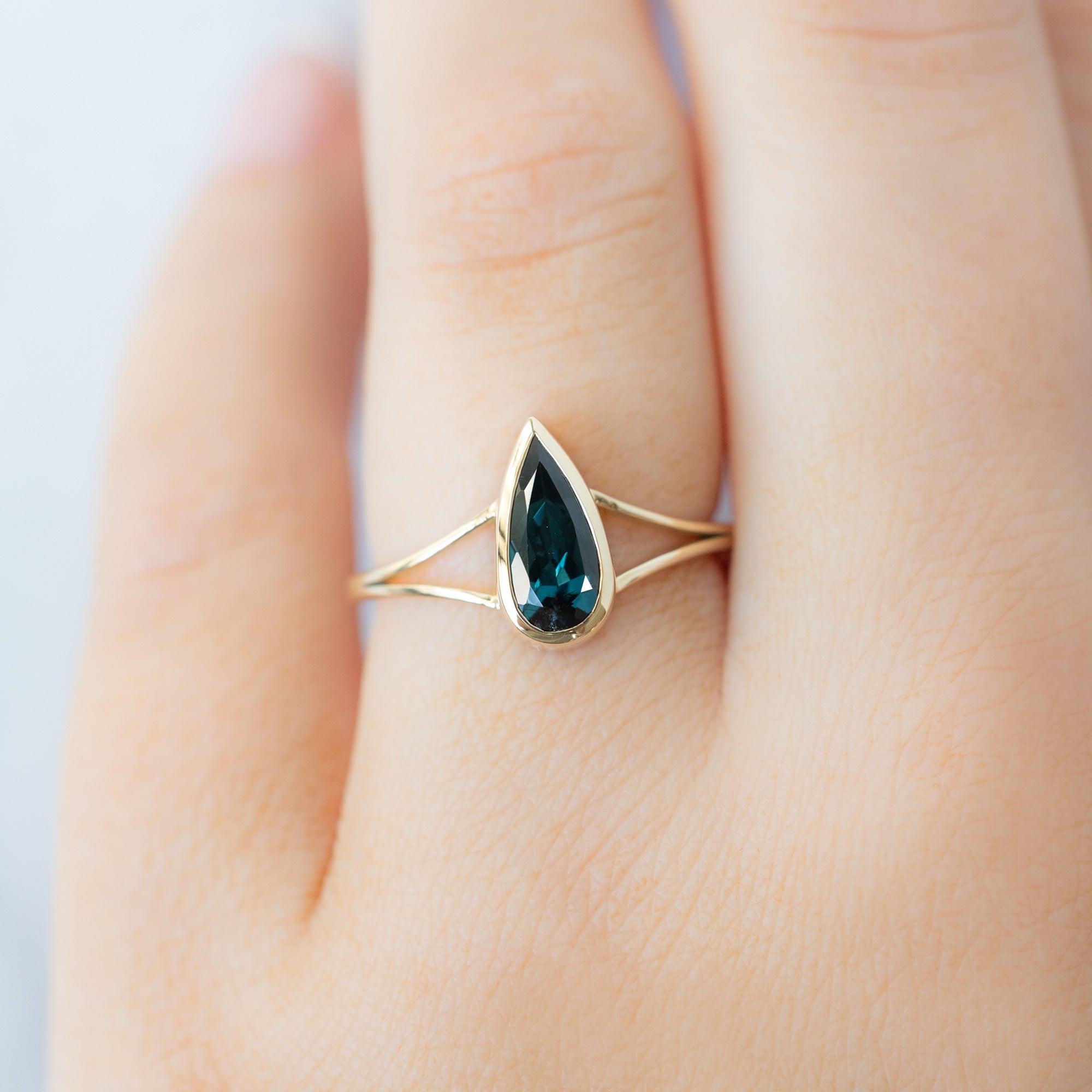 The Magnolia Ring with a 1.48ct Pear Blue Sapphire in 14K Yellow Gold on Model