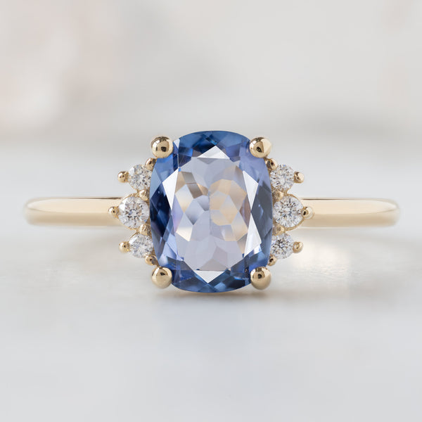The Sunflower Ring with a 1.02ct Cushion Cut Tanzanite in 14K Yellow Gold on White Marble Surface