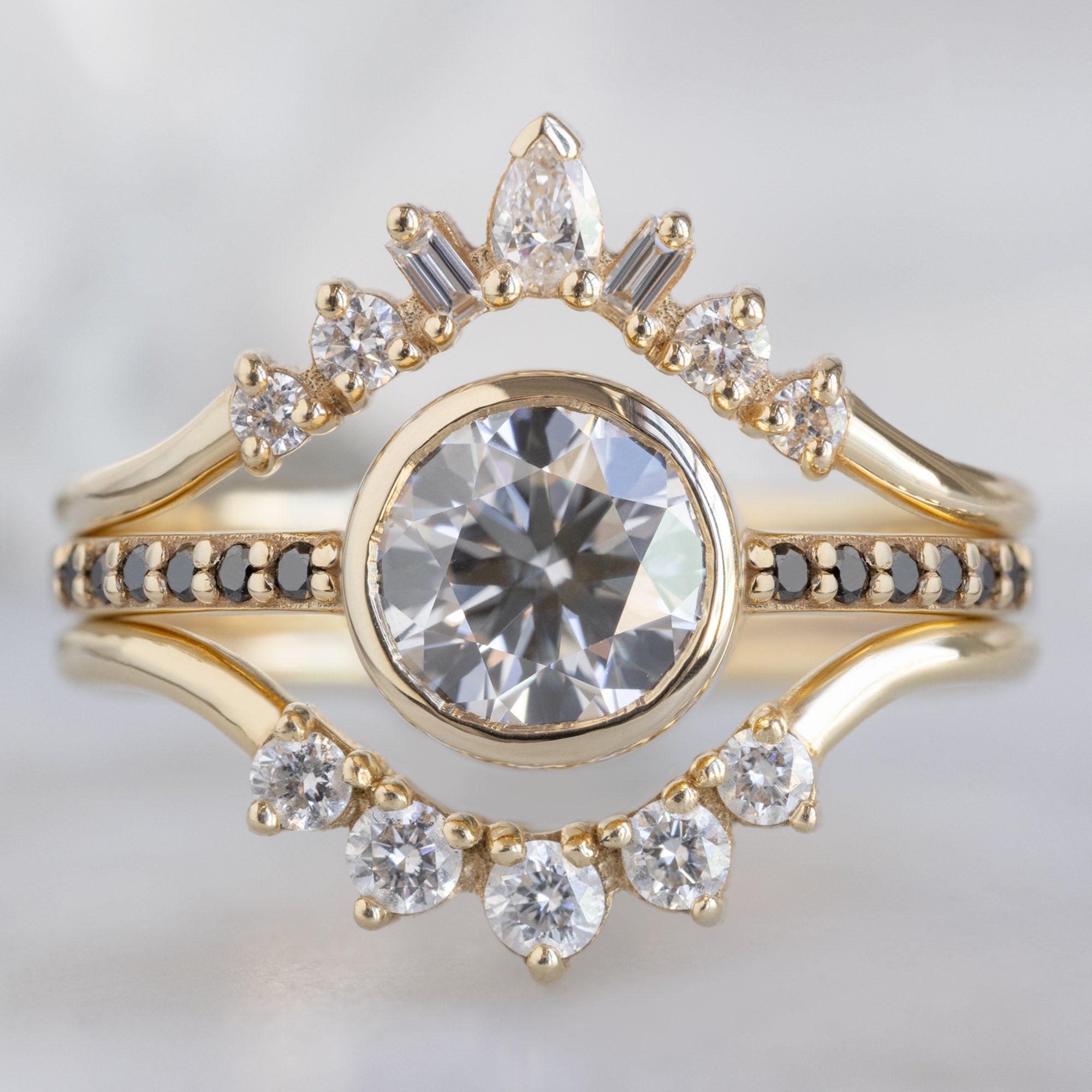 The Willow Ring with a 1.00ct Round Lab Grown White Diamond in 14K Yellow Gold Stacked with White Diamond Stacking Bands on White Marble Surface