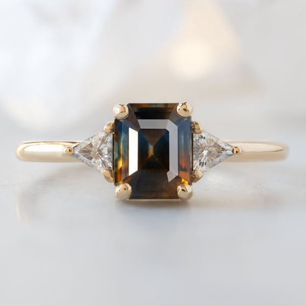 The Jade Ring with a 1.19ct Emerald Cut Parti Sapphire in 14K Yellow Gold on White Marble Surface