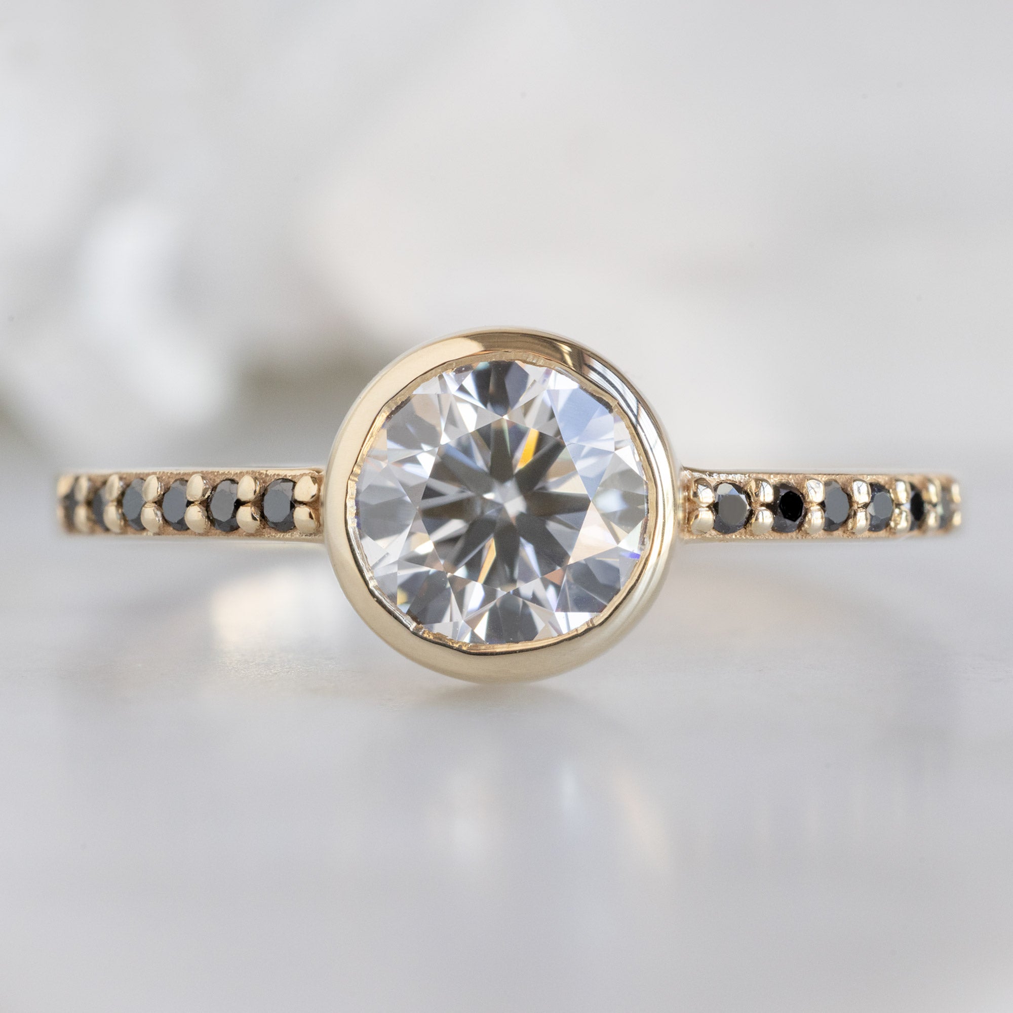 The Willow Ring with a 1.00ct Round Lab Grown White Diamond in 14K Yellow Gold on White Marble Surface