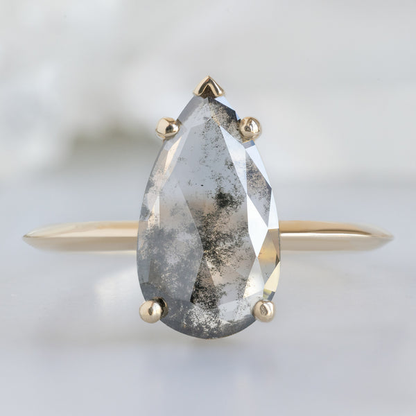 The Sage Ring with a 1.19ct Pear Lab Grown Salt and Pepper Diamond in 14K Yellow Gold on White Marble Surface