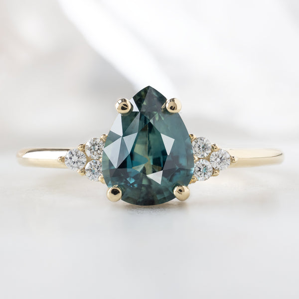 The Ivy Ring with a 1.37ct Pear Montana Sapphire in 14K Yellow Gold on White Marble Background