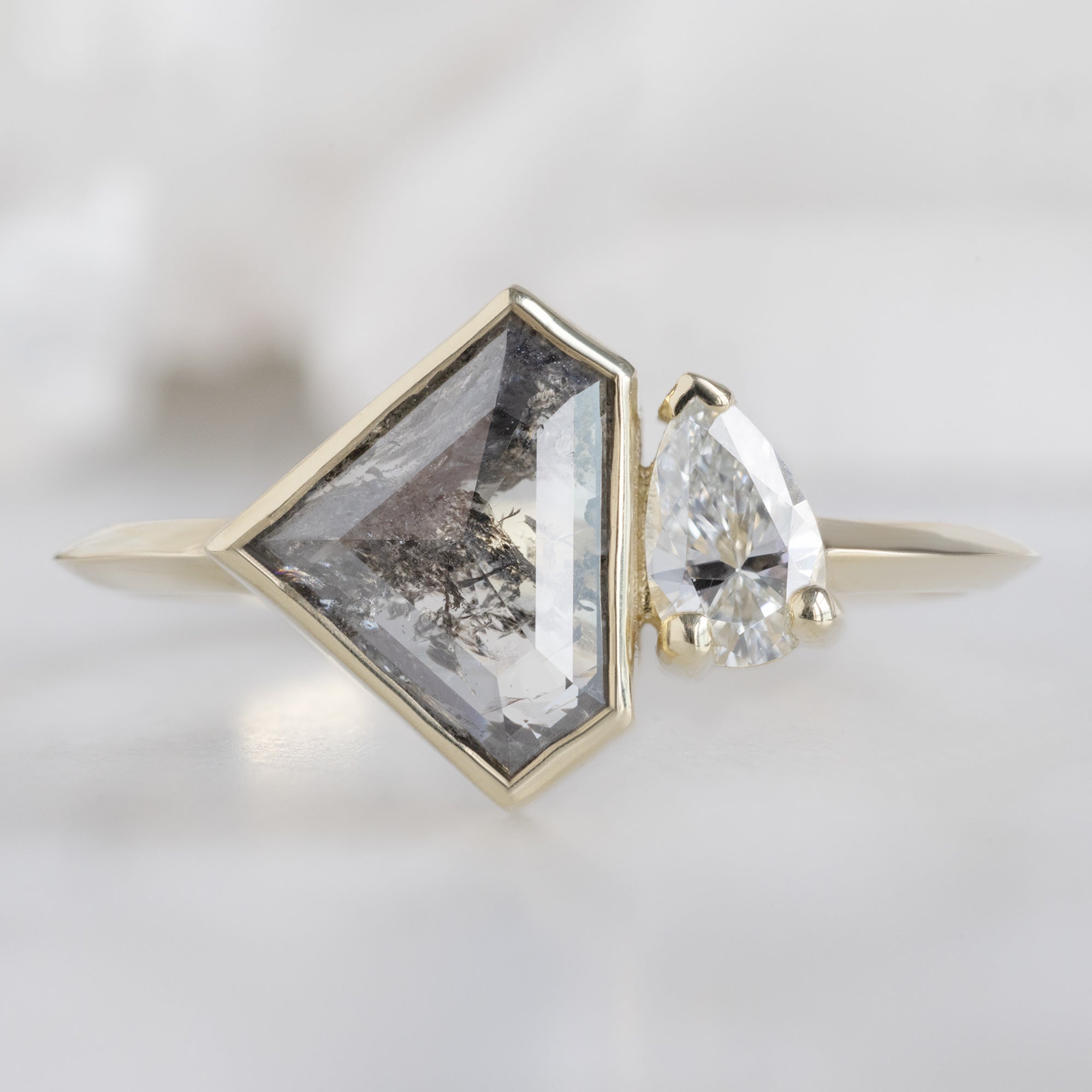 The You and Me Ring with a 1.35ct Shield Salt and Pepper in 14K Yellow Gold on White Marble Surface
