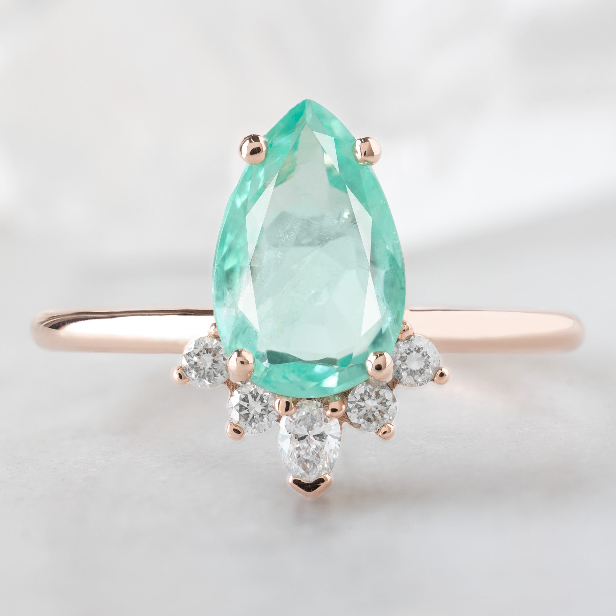 The Aster Ring with a 1.48ct Pear Emerald in 14K Rose Gold on White Marble