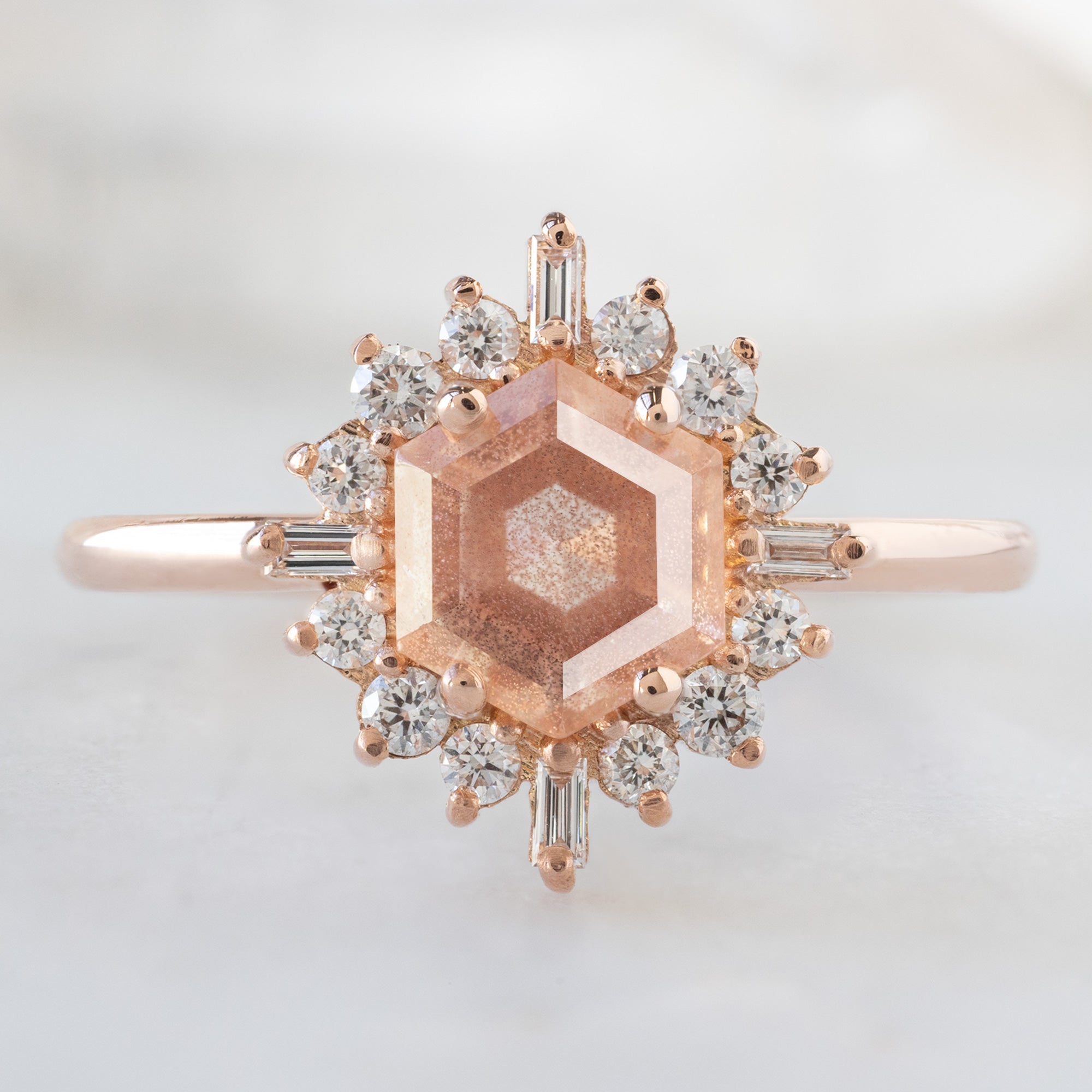 The Compass Ring with a 0.98ct Hexagon Sunstone in 14K Rose Gold on White Marble Surface