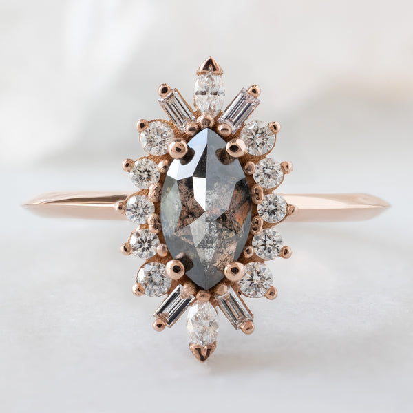 The Camellia Ring with a .66ct Marquise Salt and Pepper Diamond in 14K Rose Gold on White Marble Surface