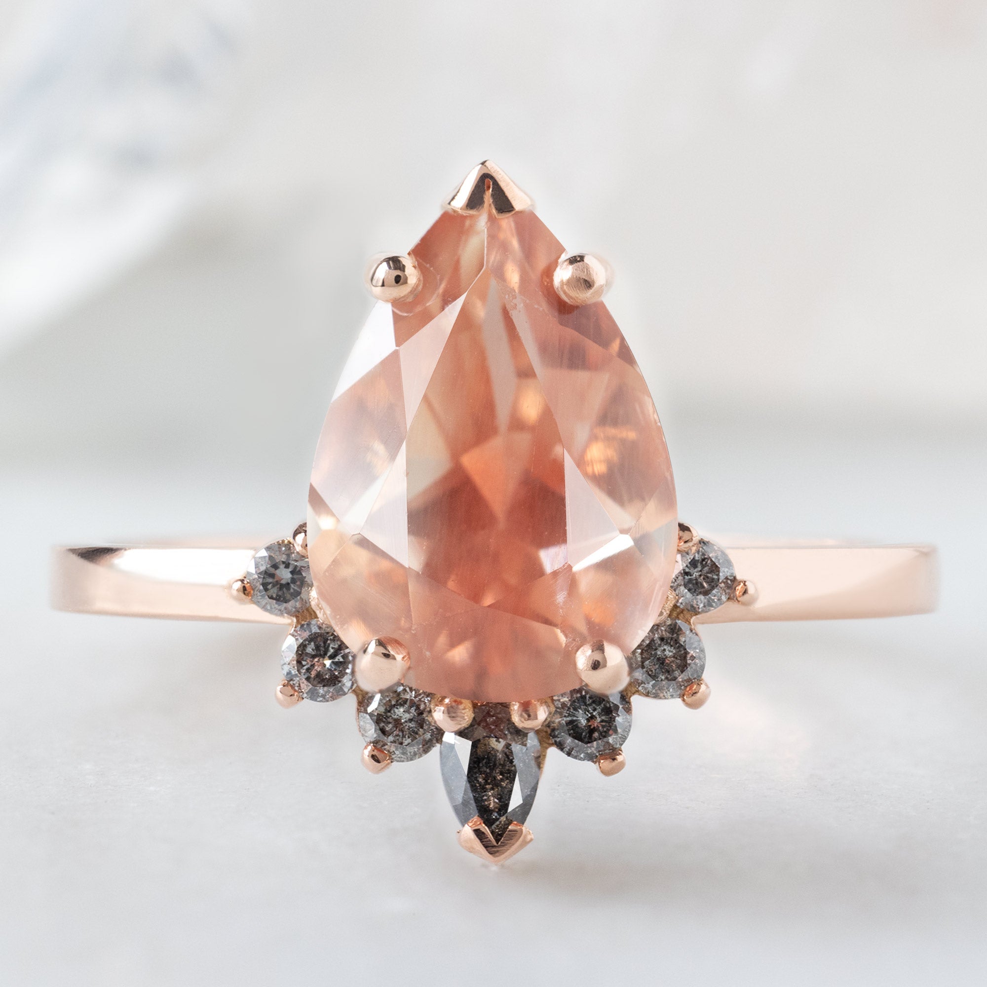 The Aster Ring with a 1.90ct Pear Oregon Sunstone in 14K Rose Gold on White Marble Surface