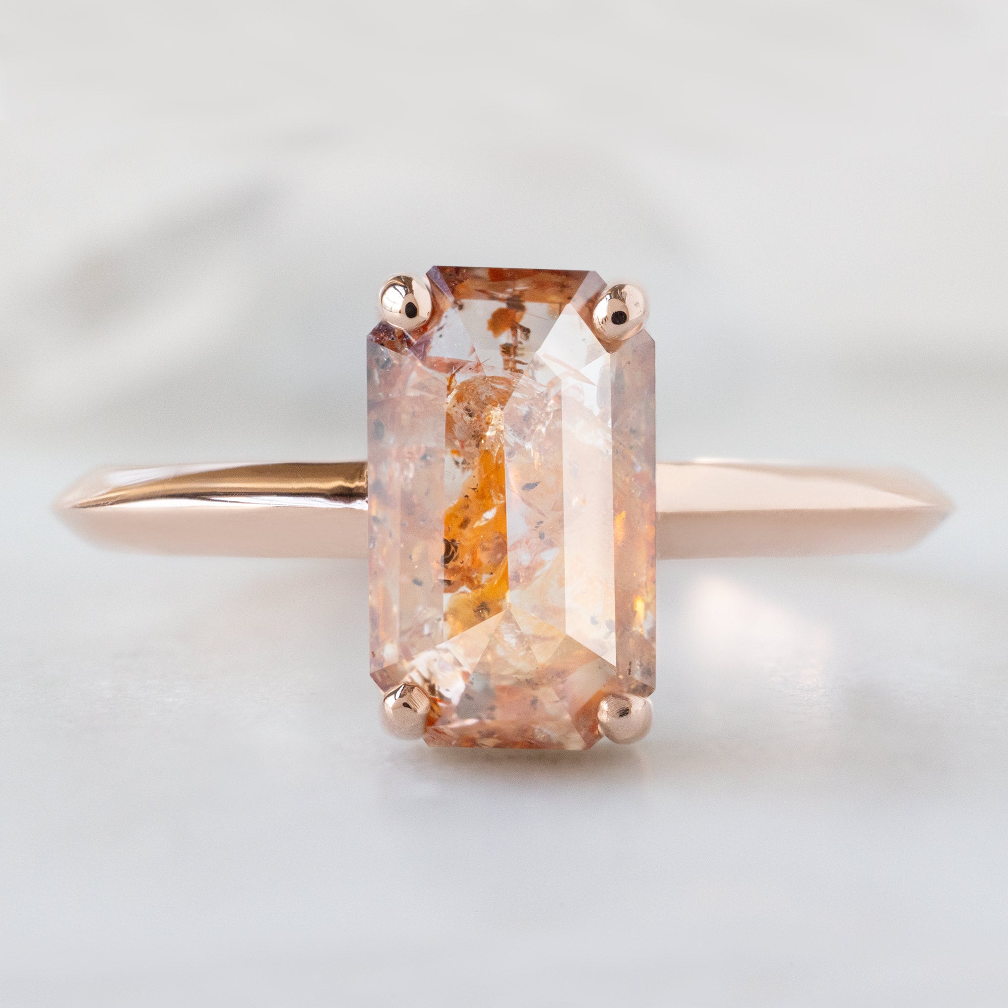 The Bryn Ring with a 2.01ct Emerald Cut Red Diamond in 14K Rose Gold on White Marble Surface
