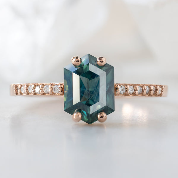 The Willow Ring with a 1.28ct Hexagon Blue Sapphire in 14K Rose Gold on White Marble Surface
