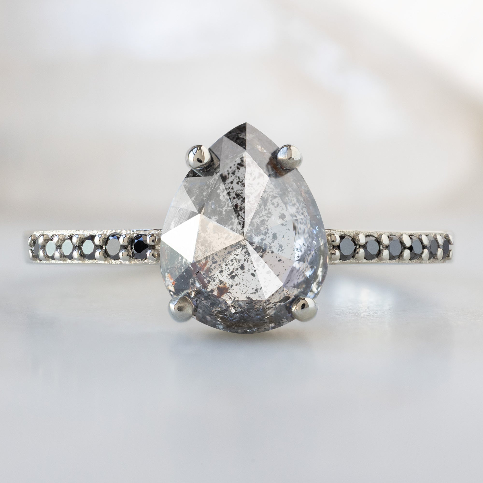 The Willow Ring with a 1.56ct Pear Salt and Pepper Diamond in 14K White Gold on White Marble Surface