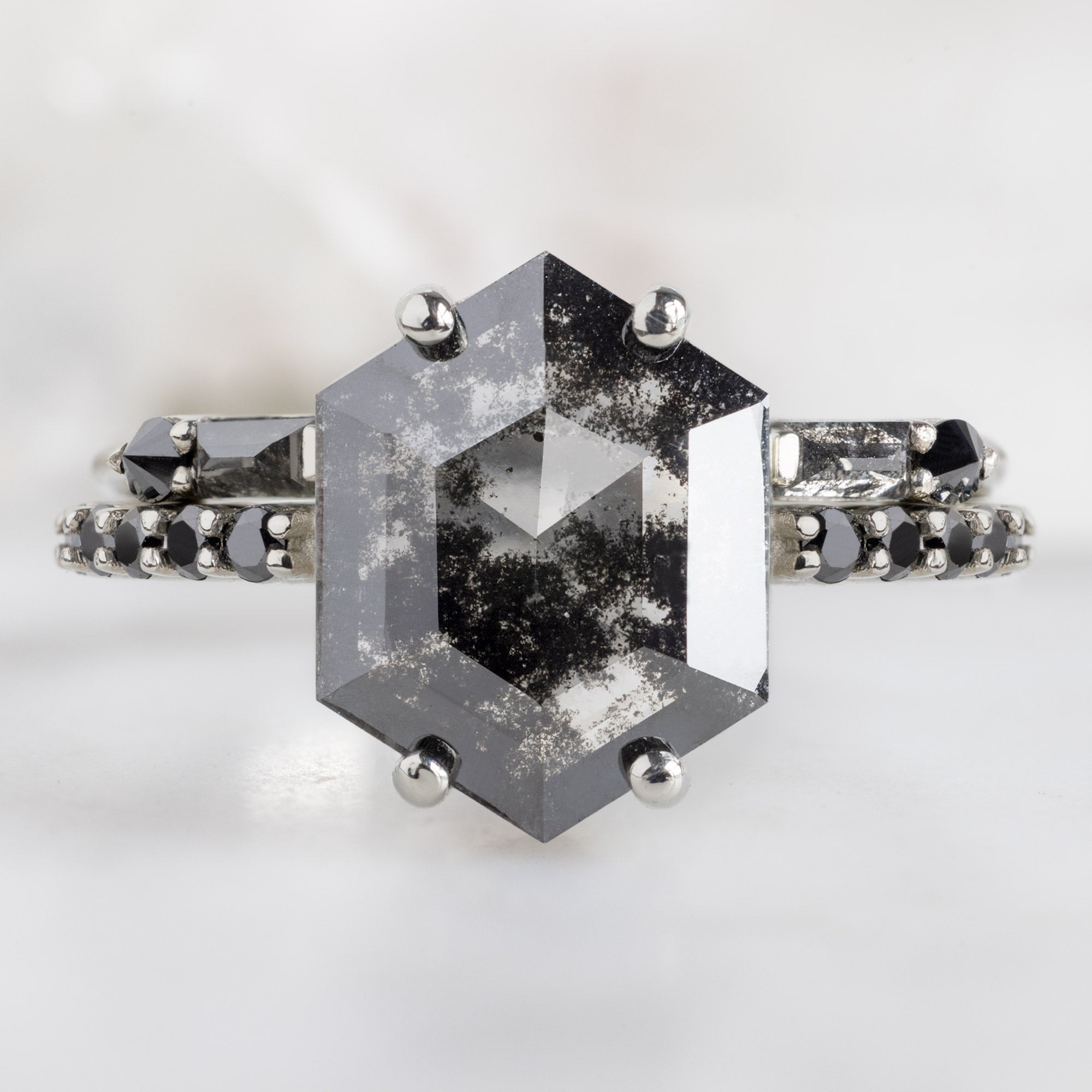 The Luxe Willow Ring with a 2.17ct Lab Grown Salt and Pepper Hexagon Diamond in 14K White Gold Stacked with the Luxe Open Cuff Baguette Diamond Stacking Band on White Marble Surface