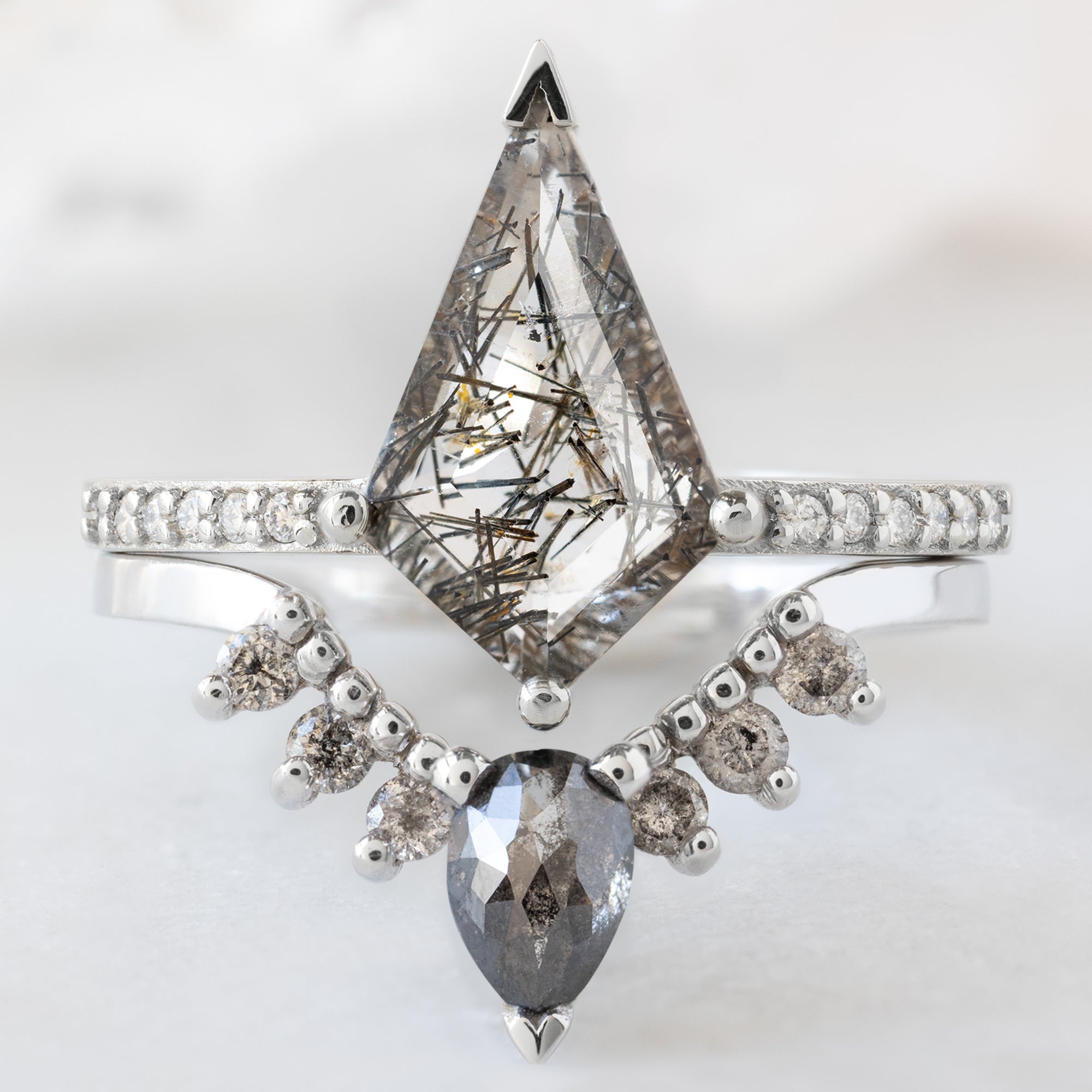 The Willow Ring with a 1.15ct Kite Tourmaline in Quartz in 14K White Gold  Stacked with the Black and Sale and Pepper Diamond Sunburst Stacking Band on White Marble Surface