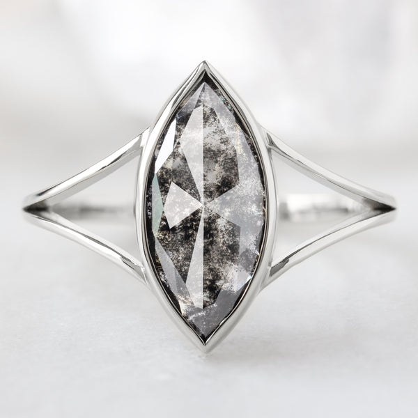 The Magnolia Ring with a 1.68ct Marquise Lab Grown Salt and Pepper Diamond in 14K White Gold on White Marble Background