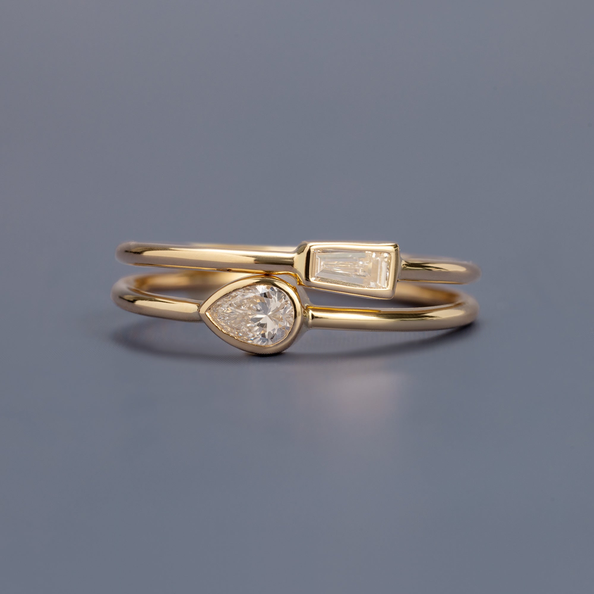 The Diamond Capsule Stack Rings in 10K Yellow Gold on Pale Blue Background