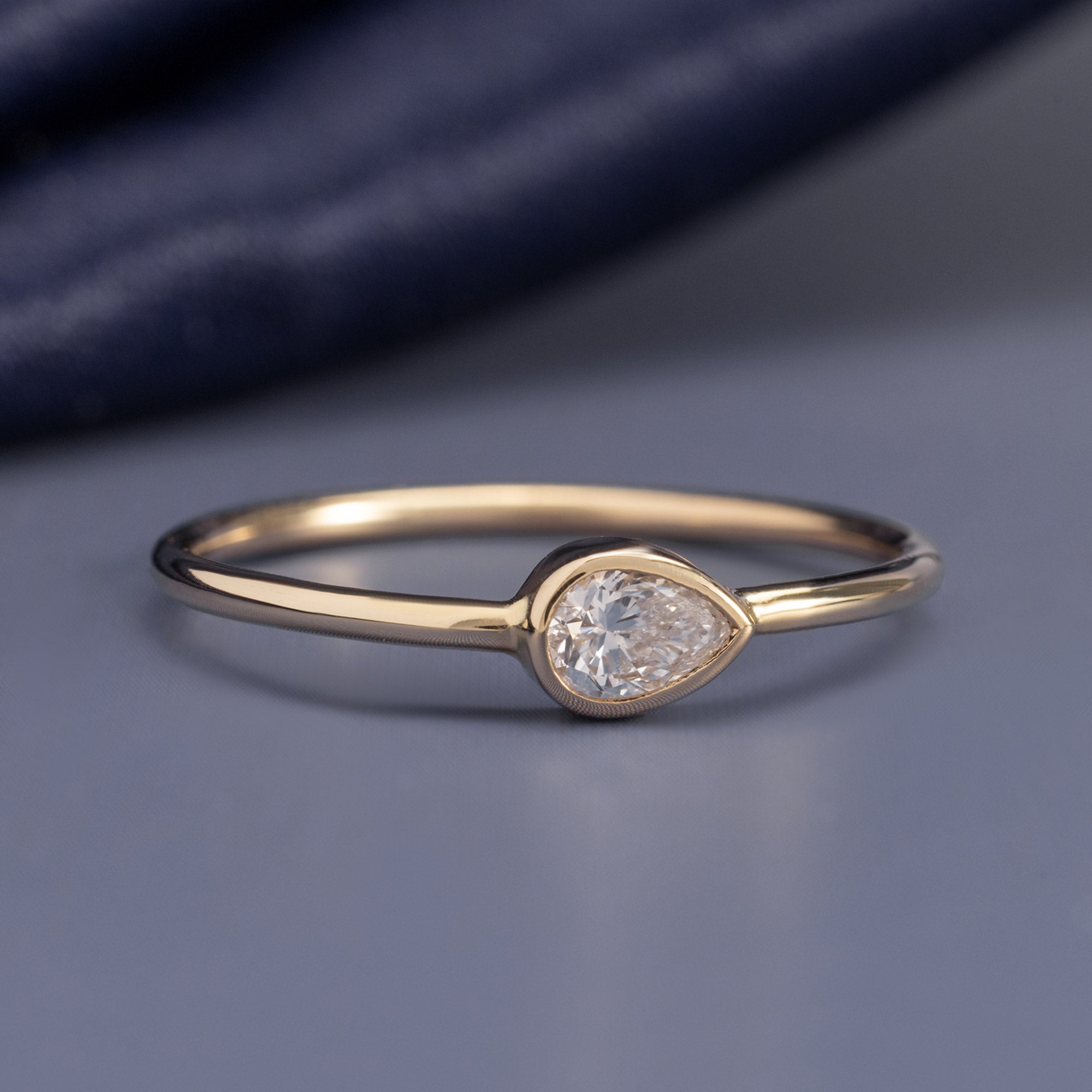 The Diamond Capsule Stack Pear Ring in 10K Yellow Gold on Blue Background