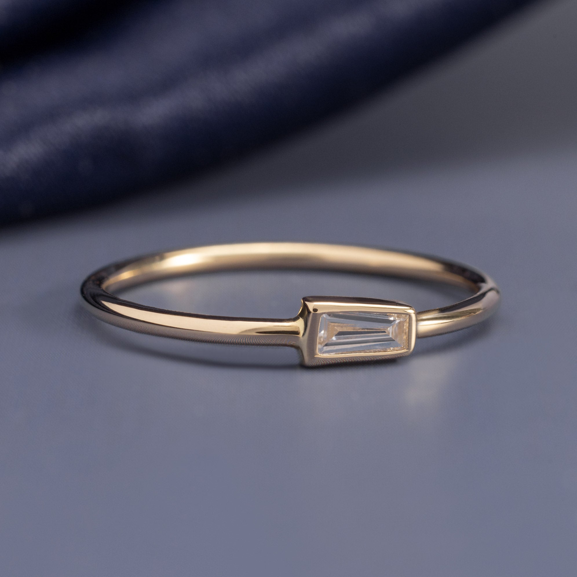 The Diamond Capsule Stack Baguette Ring in 10K Yellow Gold on Blue Background