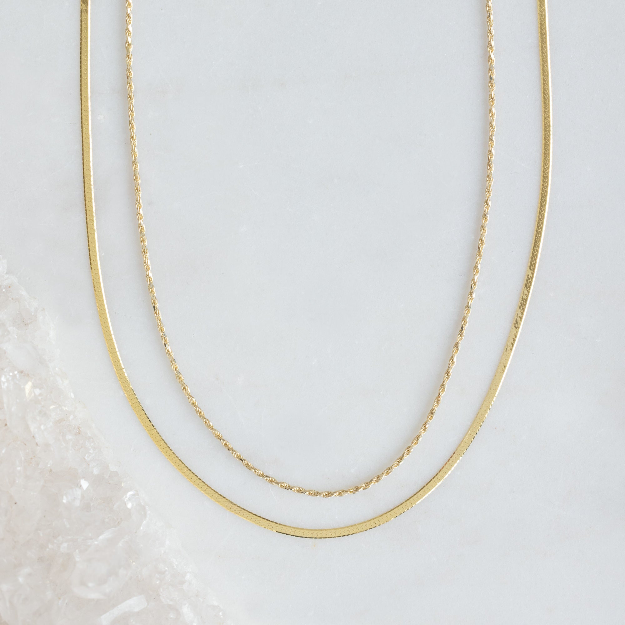 The Layering Chain Set in 14K Yellow Gold on White Marble Surface