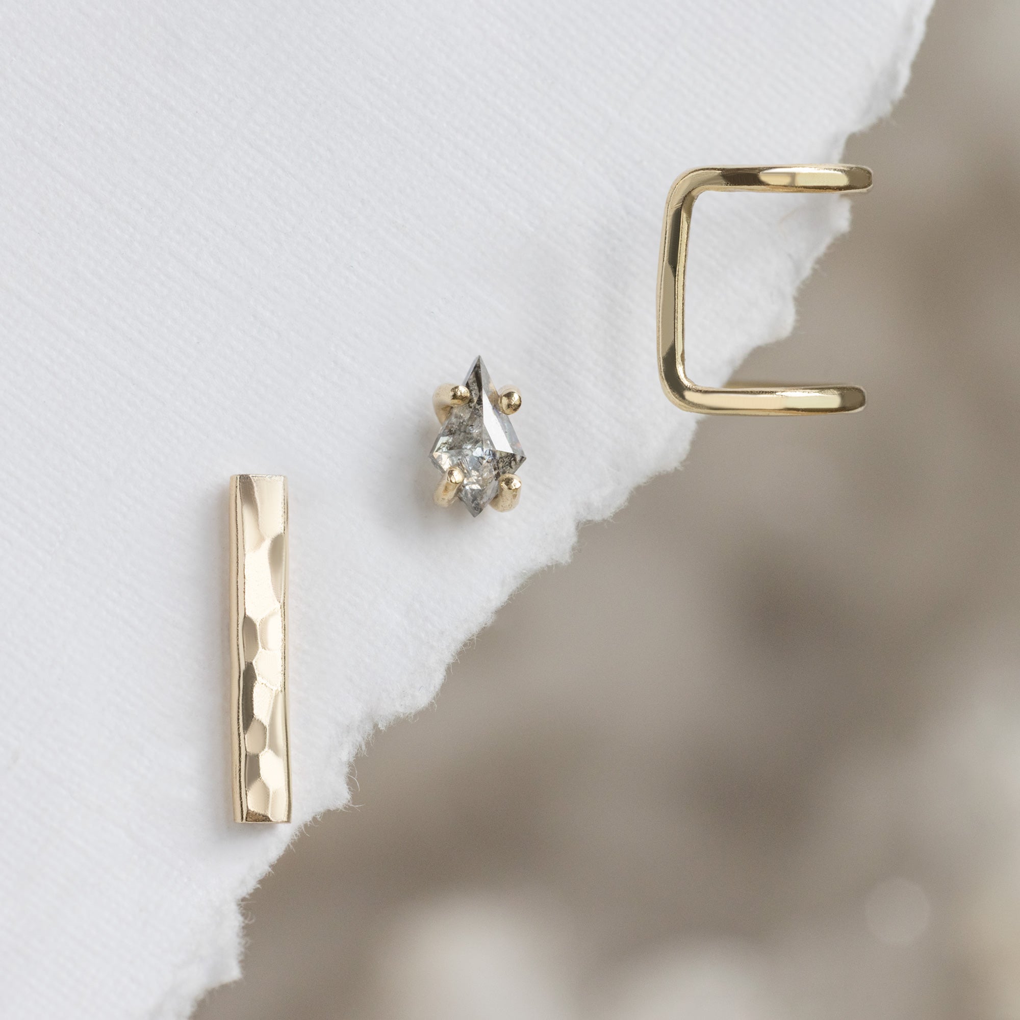 The Earscape Set in yellow gold hanging on torn white textured paper