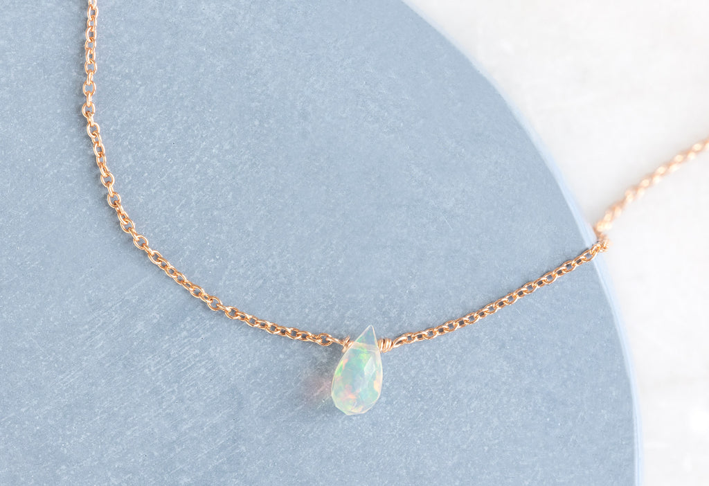 Natural Opal Teardrop Bracelet in Rose Gold on Blue and White Background