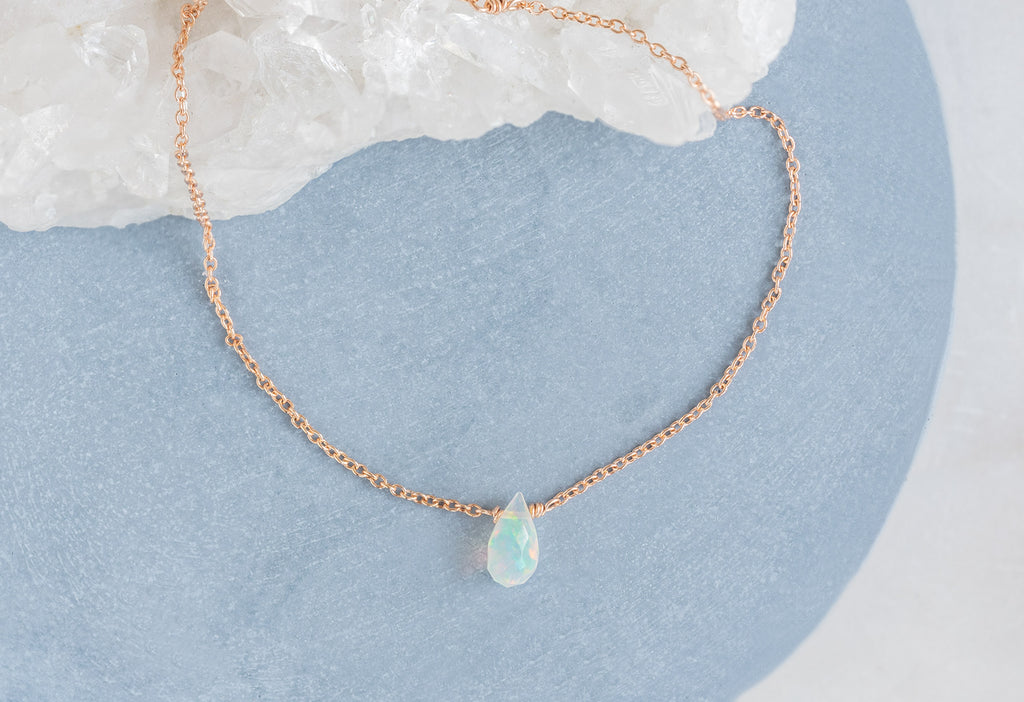 Natural Opal Teardrop Bracelet in Rose Gold on Blue Background with White Crystal