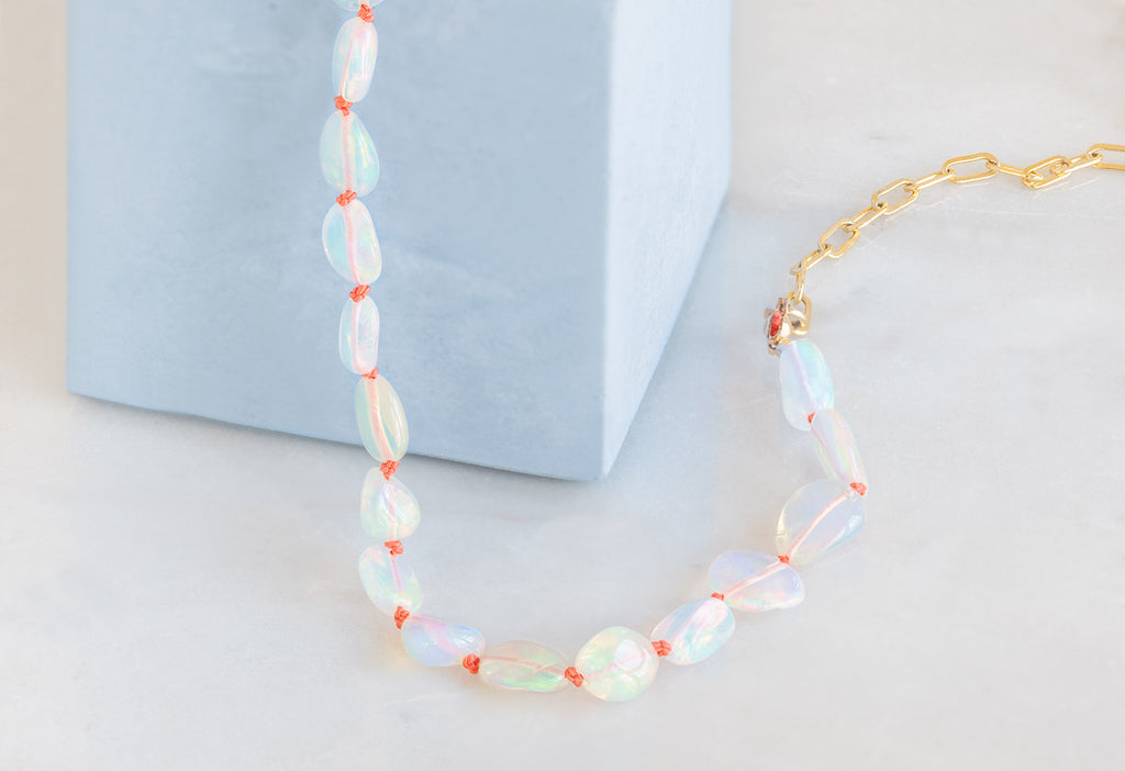 Knotted Opal Necklace on White Marble Tile and Sky Blue Concrete Block