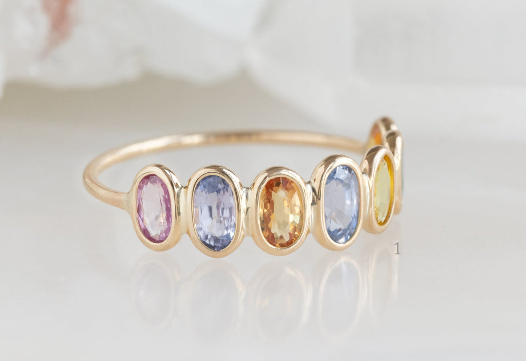 Side View of Rainbow Sapphire Gemstone Eternity Band on White Marble Tile