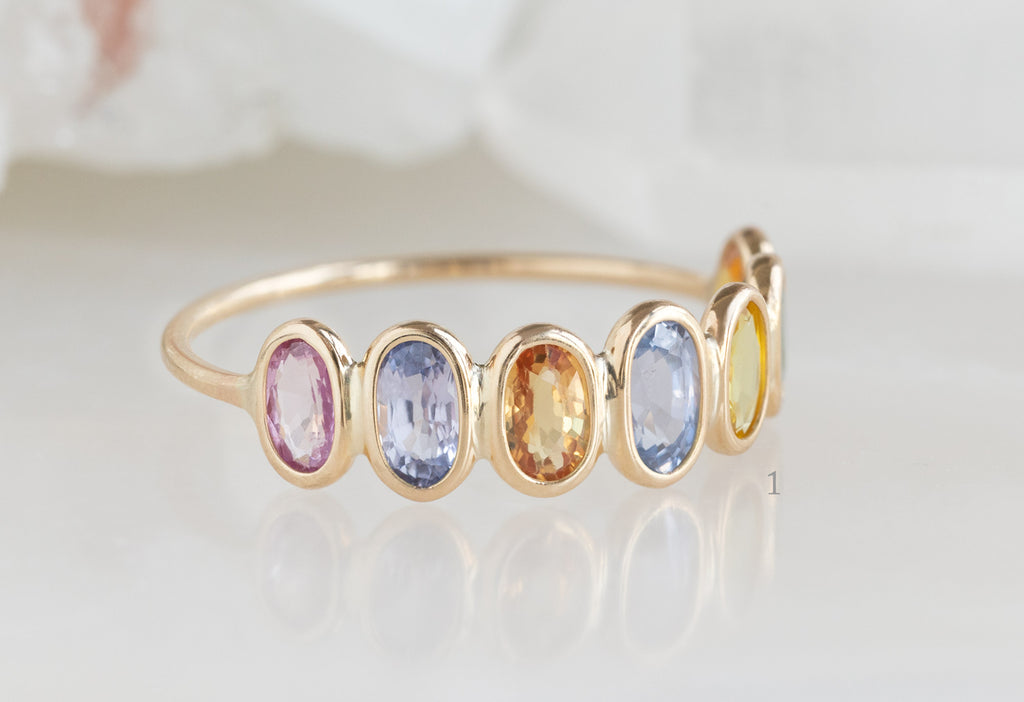 Side View of Rainbow Sapphire Gemstone Eternity Band on White Marble Tile
