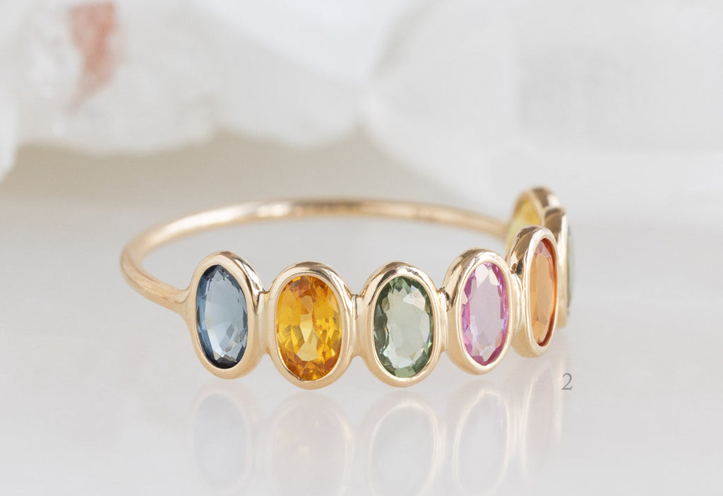 Side View of Rainbow Sapphire Gemstone Eternity Ring on white marble tile