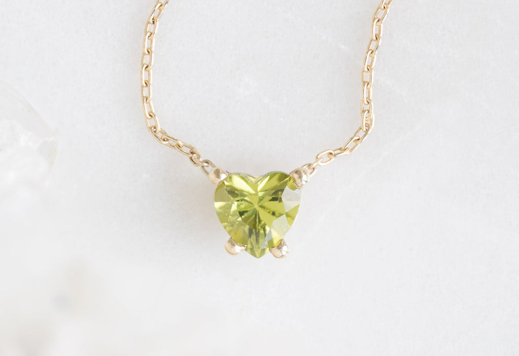 Yellow Gold Sweetheart Peridot Necklace on White Marble Tile
