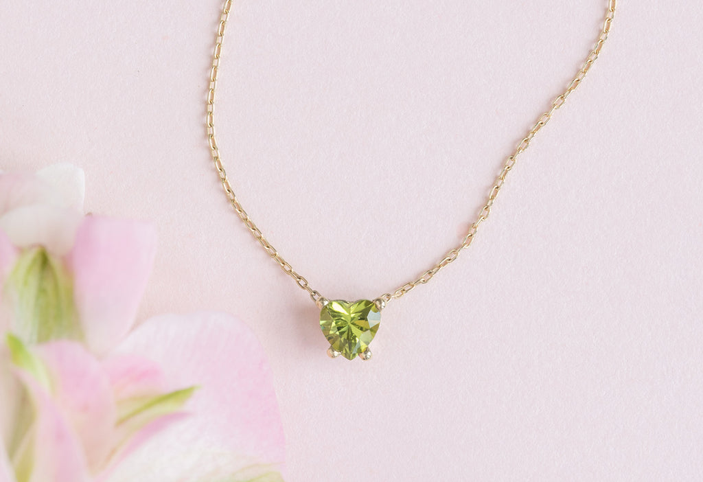 Sweetheart Peridot Necklace with Pink Flower Petals in Background